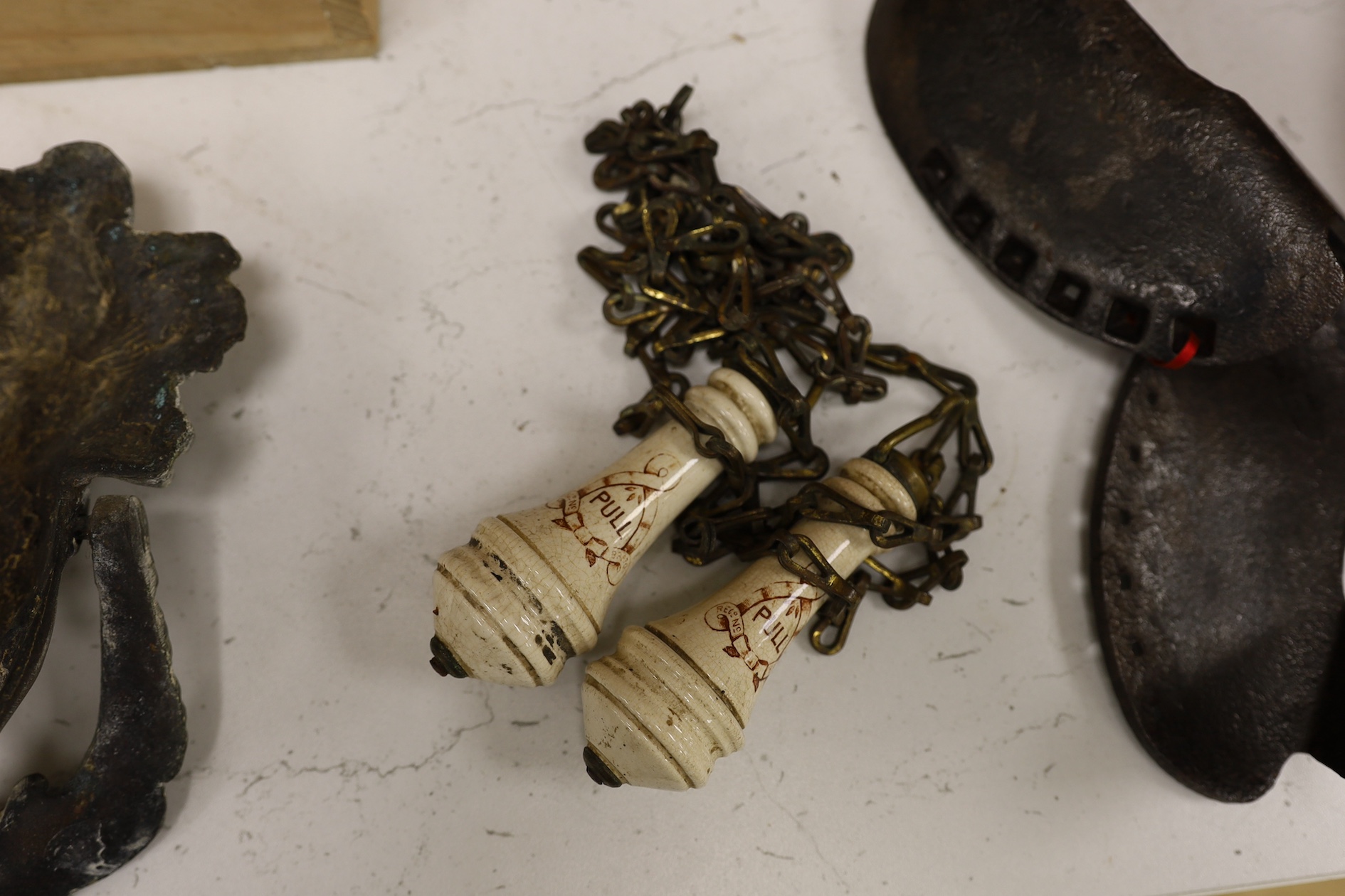 A cast iron toy model of a tricycle, a carved wooden bow, a classical figurative door knocker, a pair of metal cow shoes and two ceramic cistern pulls, bowl 30cm diameter. Condition - fair